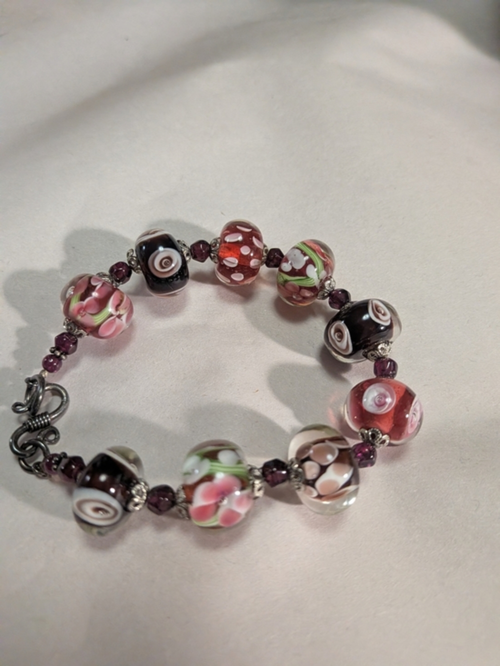 handmade bracelet features lampwork glass beads in reds/Purples 925 Clasp